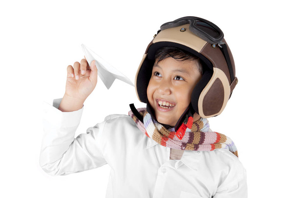 Lächelnder asiatischer Junge mit Helm, der ein Flugzeugpapier hält - Foto, Bild