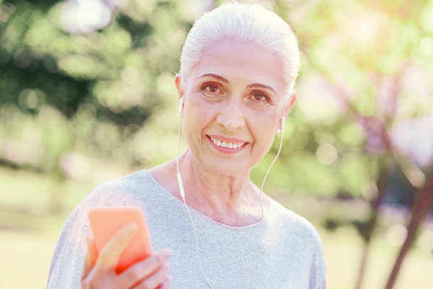 Close up of elderly woman listening to music - Фото, изображение