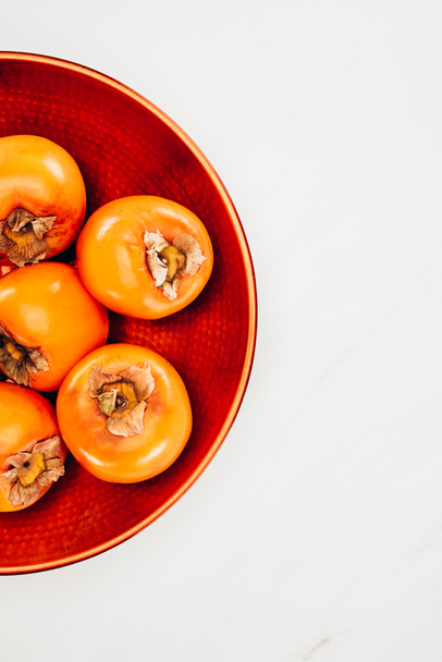 top view of persimmons on red plate isolated on white - Photo, Image