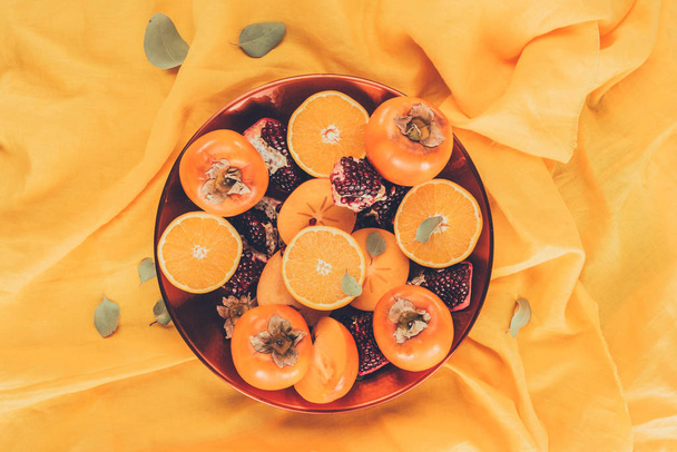 bovenaanzicht van vruchten op plaat op oranje tafellaken - Foto, afbeelding
