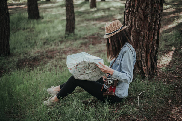 молодая девушка-туристка с картой в лесу
  - Фото, изображение