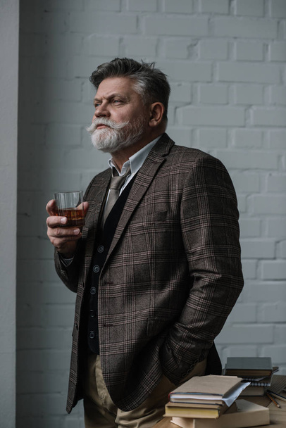 senior man in tweed suit with glass of whiskey looking away - Fotó, kép