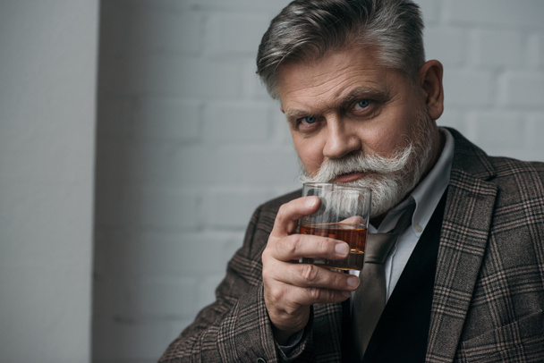 close-up portrait of senior man in tweed suit with glass of whiskey - 写真・画像