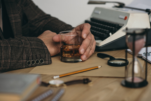 recortado tiro de escritor senior con vaso de whisky en el lugar de trabajo
 - Foto, imagen