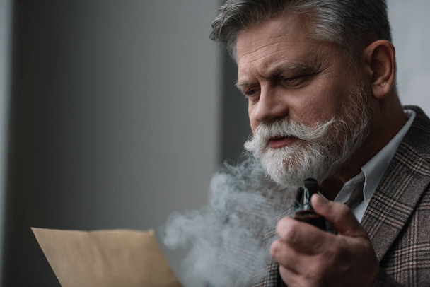 bearded senior man smoking pipe and reading letter - Valokuva, kuva