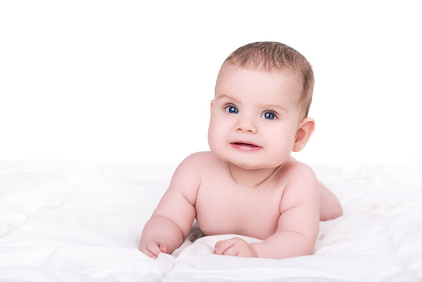 adorable smiling baby girl or boy with blue eyes lying on soft b - 写真・画像