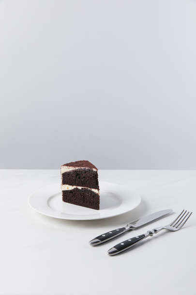 Pastel de chocolate en el plato y tenedor con cuchillo
  - Foto, Imagen