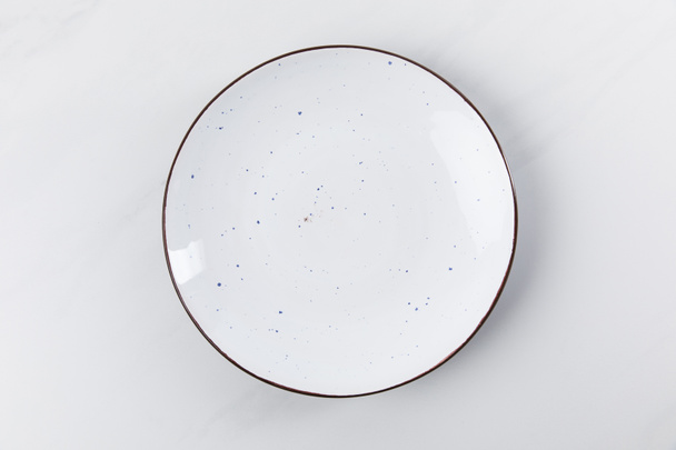 Imagen de vista superior de la placa colocada en la superficie blanca, concepción minimalista
 - Foto, Imagen