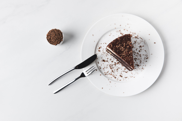 Bowl with grated chocolate and cake on plate  - Valokuva, kuva