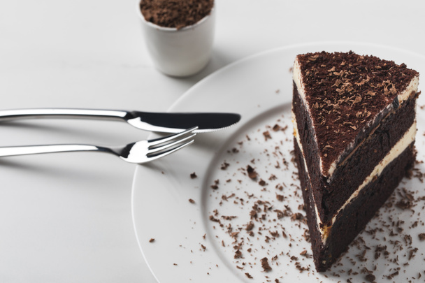 Ruokailuvälineet lautasella kakku ja raastettu suklaa
 - Valokuva, kuva