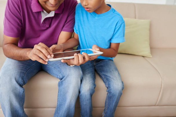 Imagen recortada del padre y el hijo utilizando la aplicación en la computadora tableta
 - Foto, imagen