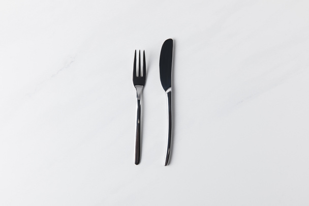 Garfo e faca colocados na superfície branca, concepção de compromissos de mesa
 - Foto, Imagem