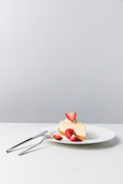 Кусочки свежей клубники на тарелке с чизкейком
  - Фото, изображение
