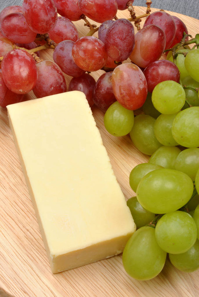primo piano di gustoso formaggio fatto in casa con uva sullo sfondo
 - Foto, immagini
