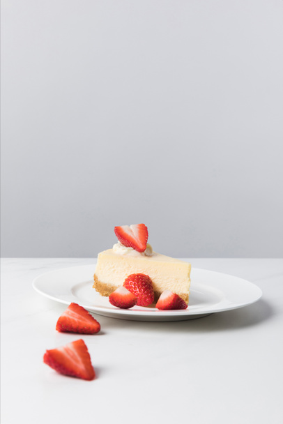 Vista de primer plano del plato con tarta de queso rodeada de fresas en rodajas en la mesa
 - Foto, imagen