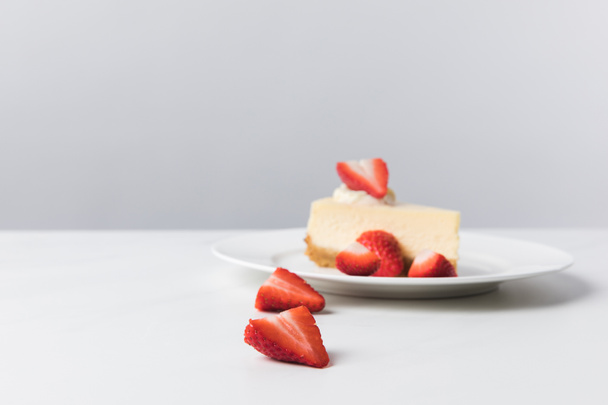Placa con tarta de queso rodeada de fresas frescas en rodajas
 - Foto, imagen