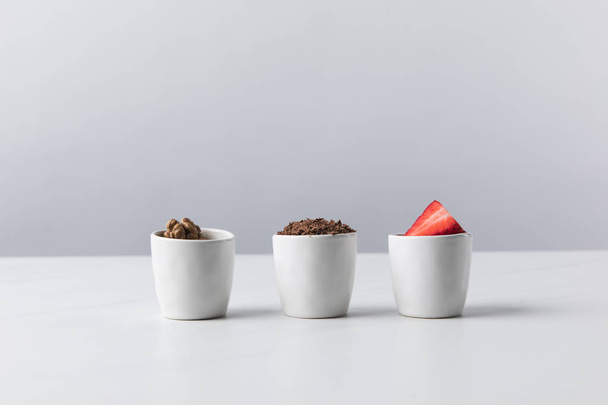 Vue de face de trois bols avec noix, chocolat râpé et fraises
  - Photo, image