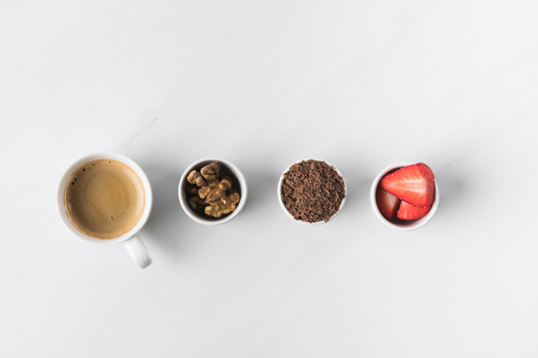 Vista superior de la taza de café y tazones con nueces, fresas y chocolate rallado
 - Foto, Imagen