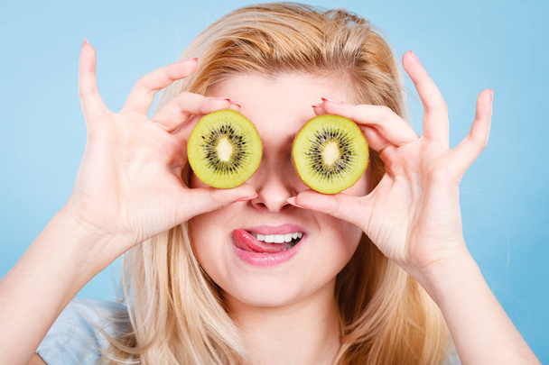 Woman holding green kiwi fruit like eyeglasses - Φωτογραφία, εικόνα