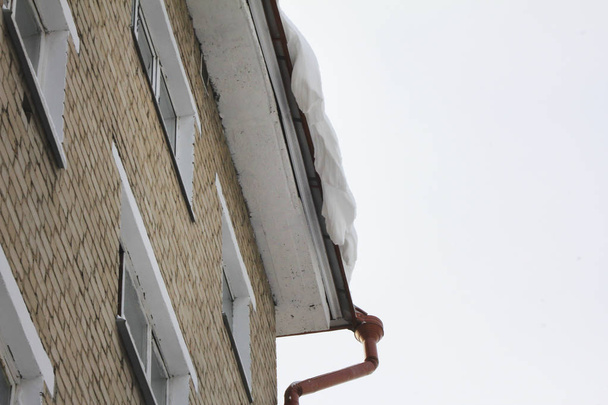 Neve perigosa cai pendurada no telhado
 - Foto, Imagem