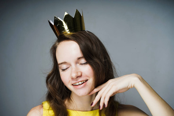 beautiful young girl with golden crown on her head smiling, eyes closed, celebrating Mother's Day - Photo, image