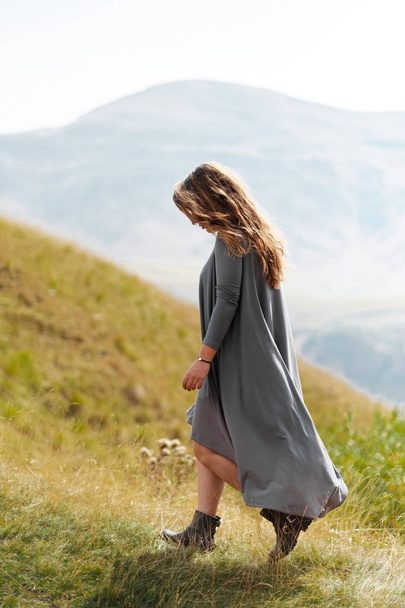 A girl in a long dress is walking around the mountains - Fotoğraf, Görsel