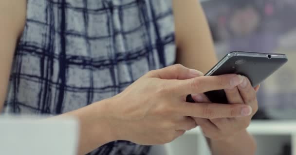 Asiatin tippt SMS auf Smartphone zu Hause. abgeschnittenes Bild einer jungen Frau, die an einem Tisch sitzt und ihr Handy benutzt. - Filmmaterial, Video