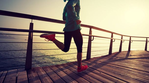 sporty fitness female runner running on seaside boardwalk during sunrise - Photo, Image