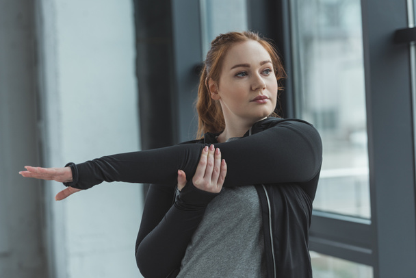 Chica con sobrepeso estirando los brazos en el gimnasio
 - Foto, imagen