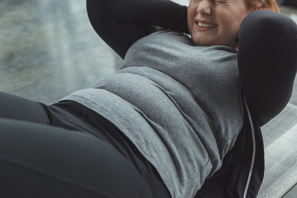 Close-up view of curvy girl performing sit ups in gym - Fotografie, Obrázek