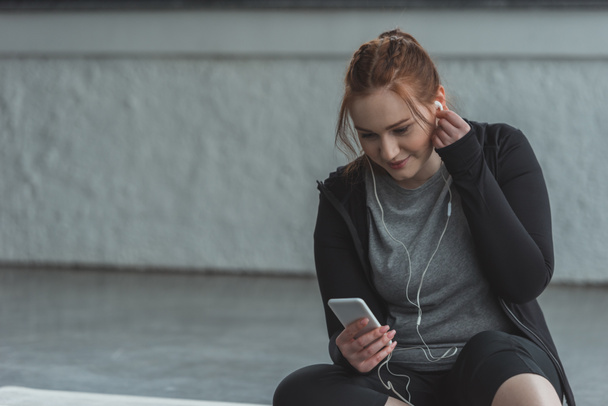 Obese girl listening to music on smartphone in gym - Φωτογραφία, εικόνα