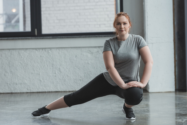 Obèse fille étirant les jambes dans la salle de gym
 - Photo, image