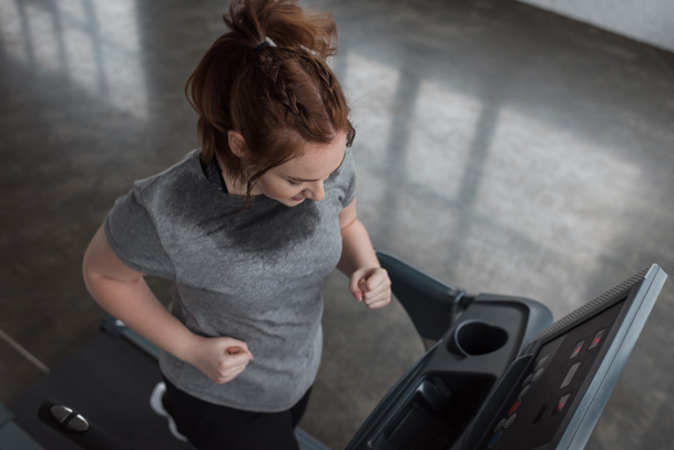 Overweight girl running on treadmill in gym - Photo, Image