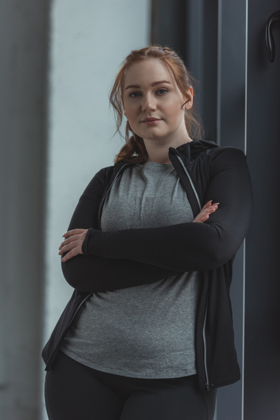 Overweight girl standing by window in gym - Foto, Imagen