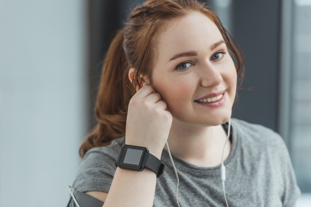 Obese girl with fitness tracker listening to music in gym - Photo, Image