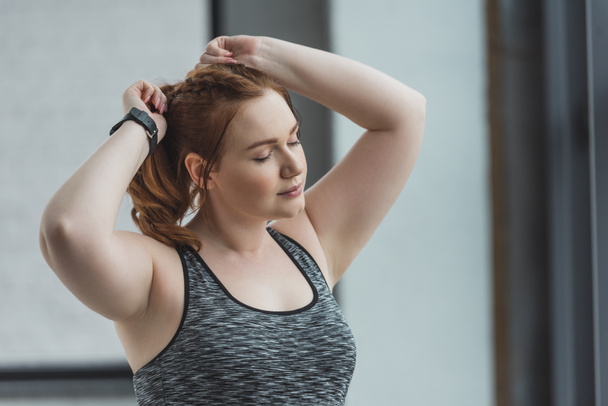 Obese girl fixing her hair in gym - Foto, Bild