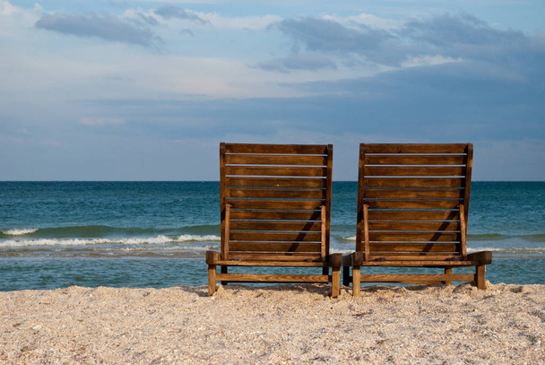 два дерев'яні коричневі шезлонг на пляжі на блакитному морі вода блакитне небо море хвиля красивий пейзаж літні канікули пляж пісочні вихідні відпочинок
 - Фото, зображення