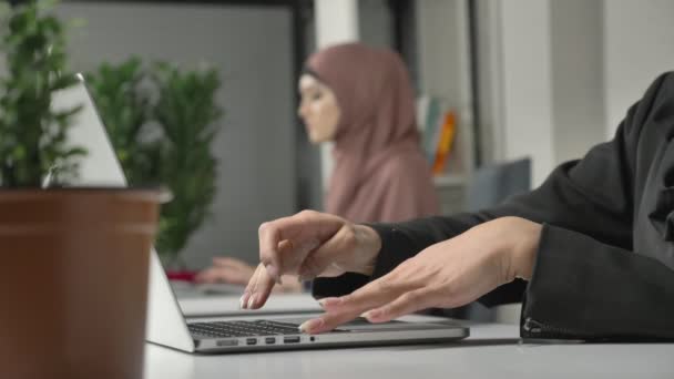 Female hands typing on the keyboard, close-up. Girl in pink hijab in the background. Office, business, work, women, concept. Arabs, Islam, hijab, religion, focus pull 60 fps - Imágenes, Vídeo