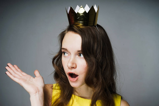lovely surprised girl with a golden crown on her head asks a question - Φωτογραφία, εικόνα