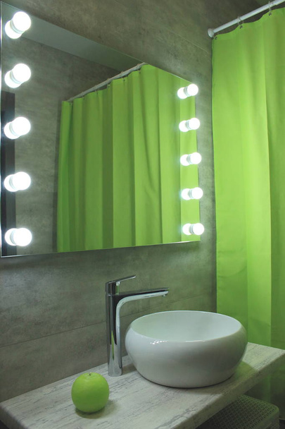 モダンなバスルームのインテリア. 大きい照らされた鏡が付いている灰色およびライト グリーンの色の浴室.  - 写真・画像