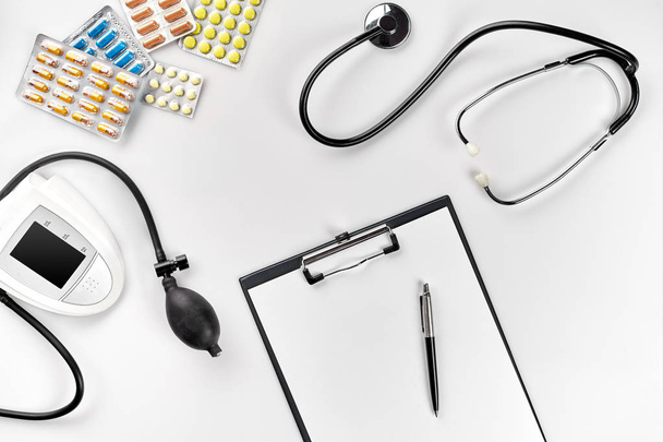 Stethoscope in the office of doctors.Top view of doctors desk table, blank paper on clipboard with pen. Copy space. Designers blank - Foto, Imagem
