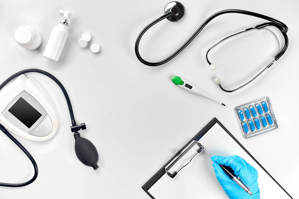 Werkplaats van een arts. Pillen in de hand, stethoscoop, Klembord en glazen op witte tafel - Foto, afbeelding