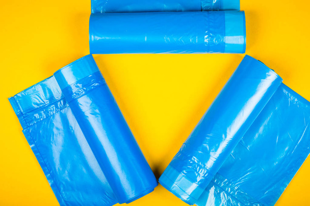 New blue garbage bags on a yellow background. - 写真・画像