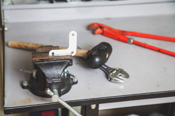 White corner clamped in vise. Behind lie mallet and wrenches - Foto, Imagem