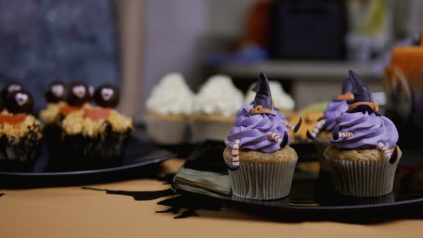 Decorating cupcake with icing hat and legs. Muffin like witch. Halloween concept - Séquence, vidéo