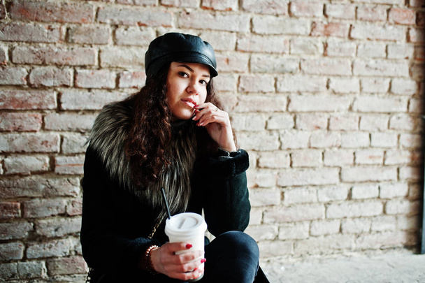 Curly mexican girl in leather cap and plastic cup of coffee at h - Foto, Imagen