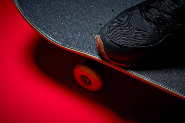 shoes and used skateboard on a red background - Foto, Imagen