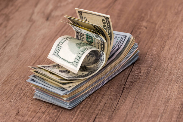 Stapel met ons dollars in contant geld in houten bureau. - Foto, afbeelding