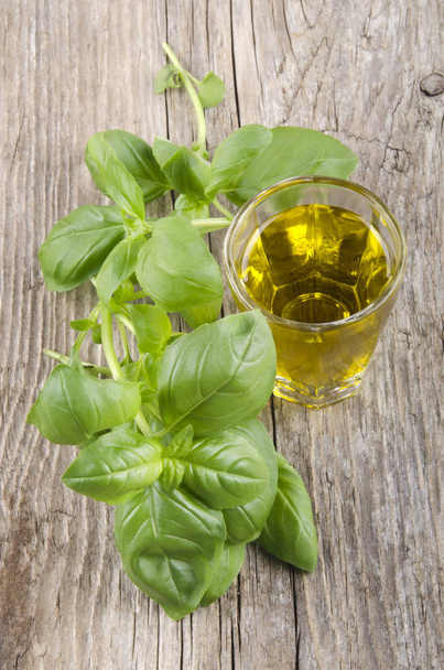 Extra Virgin Olive Oil In A Glass And Basil leaves On Wood background - Foto, Imagem