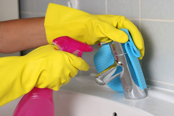manos en guantes que sostienen la botella de aerosol y el grifo de limpieza
  - Foto, imagen